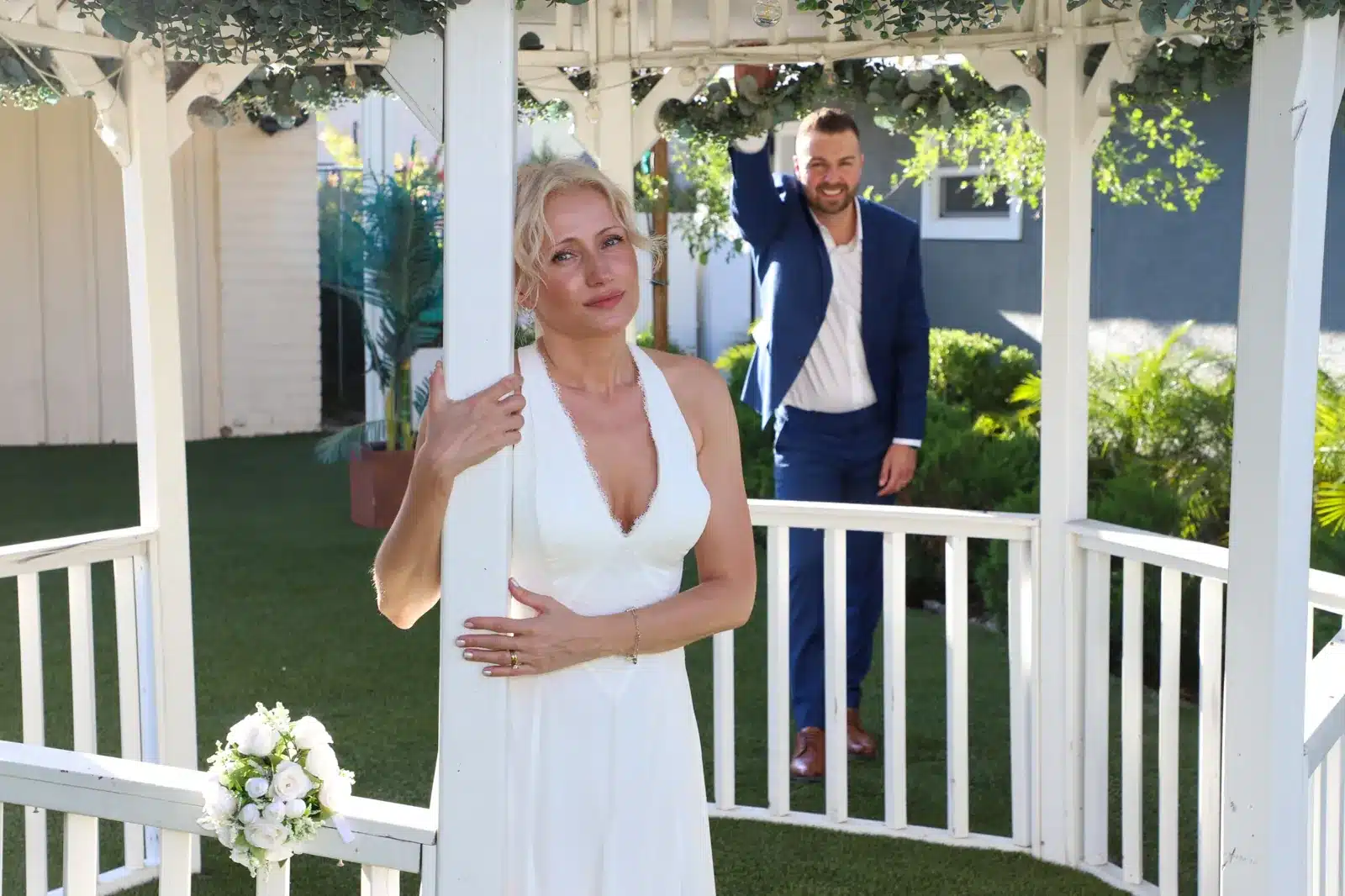 Bride posing in gazebo with groom in background at Las Vegas wedding chapel